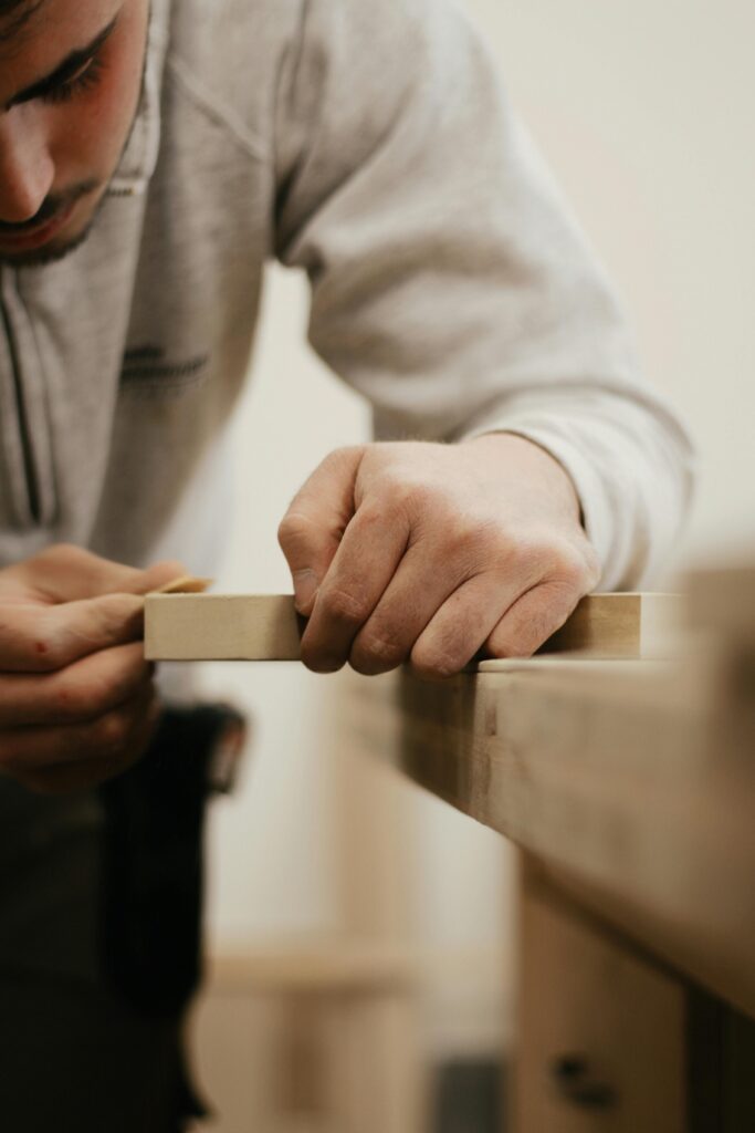 Close-up of a man meticulously sanding wood, showcasing craftsmanship.